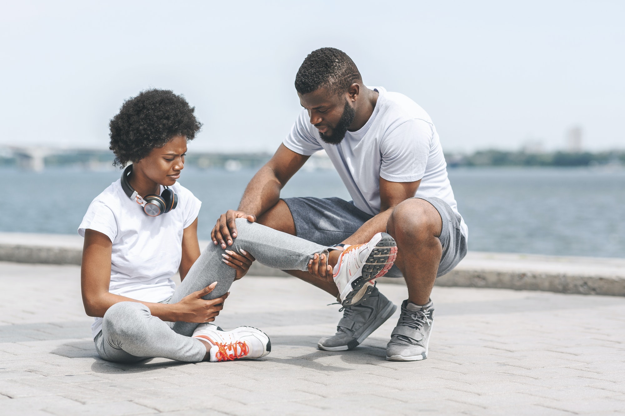Afro Guy Helping Woman With Injured Ankle At Riverbank