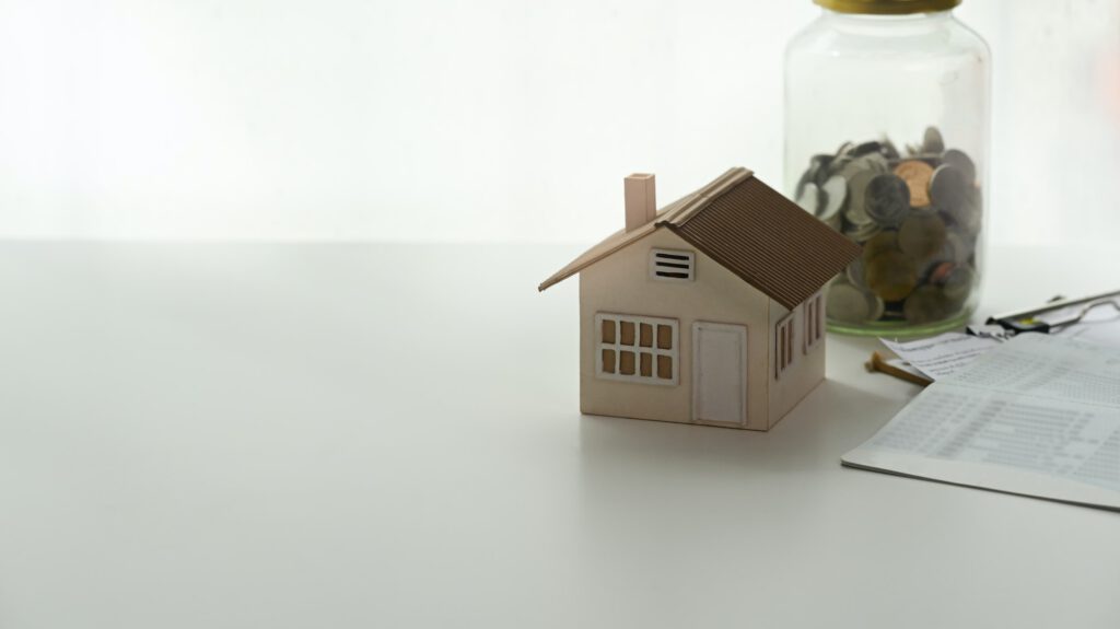Investment properties money and home ownership model toy house on white table.